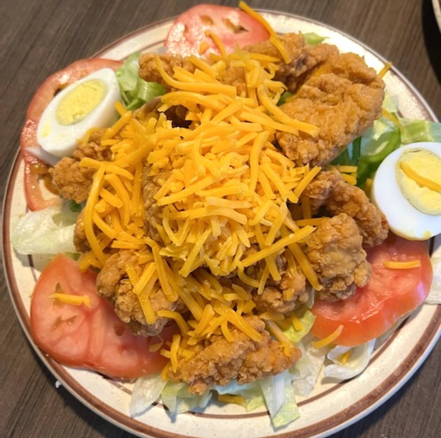 The popcorn chicken salad at the Coffee Cup is a large plate of lettuce topped with fried chicken, tomatoes, hard boiled eggs, shredded cheese and choice of dressing.