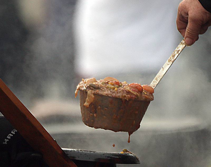 A spoonful of Burgoo is served by volunteers at the food court during the 51st annual Burgoo festival downtown Utica on Sunday Oct. 10, 2021.