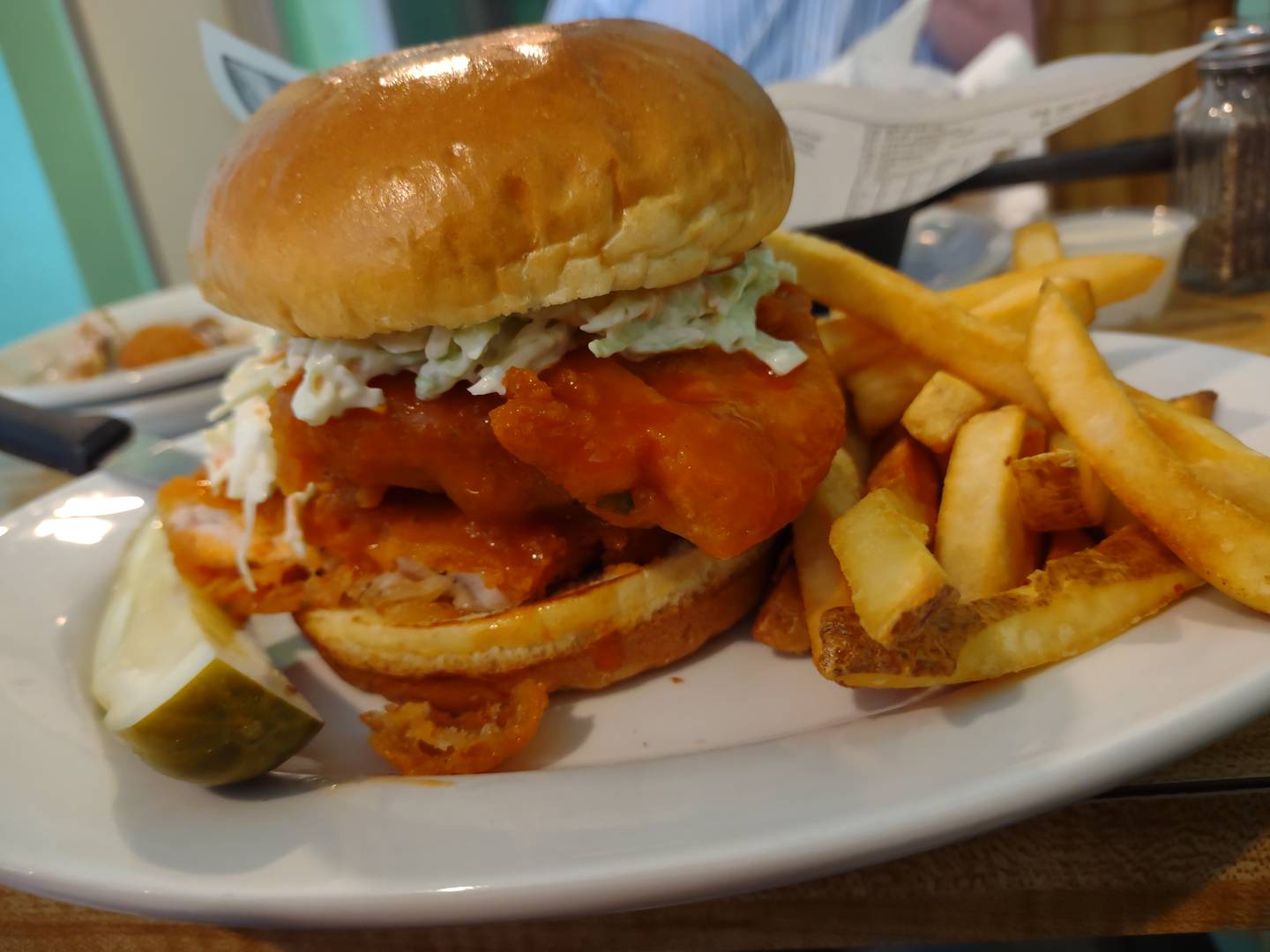 The Nashville chicken sandwich delivers a large breaded chicken breast coated in Nashville sauce and coleslaw at Maria's Cafe Bistro in Ottawa.